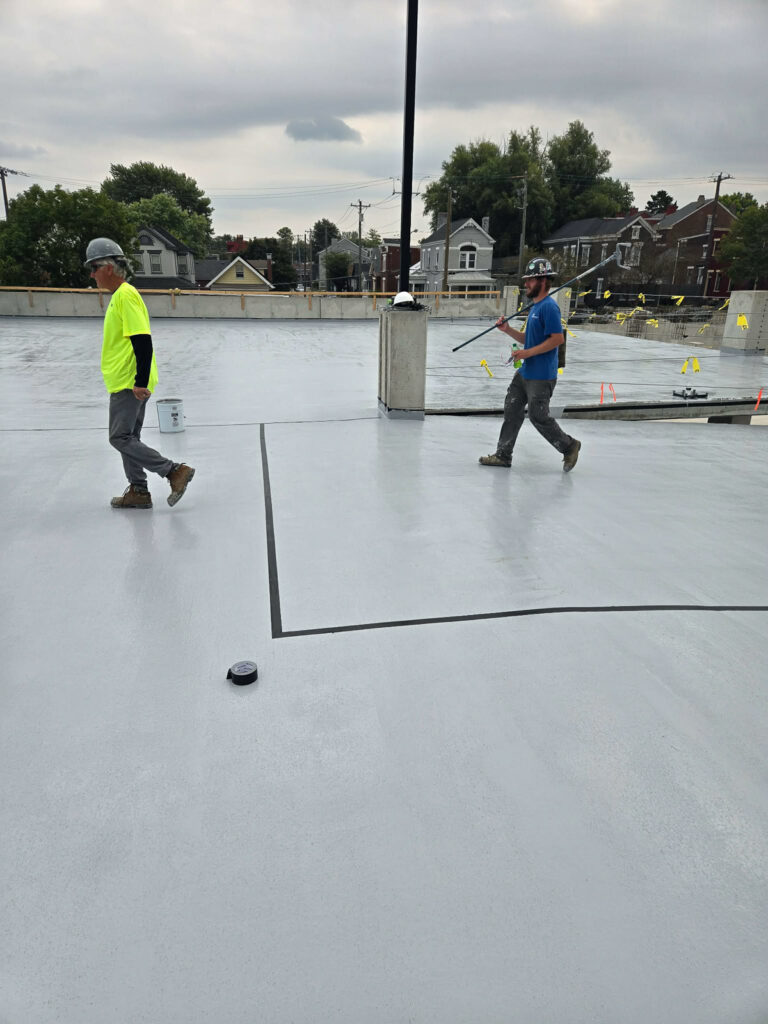Crew working with long-handled tools on a concrete deck"