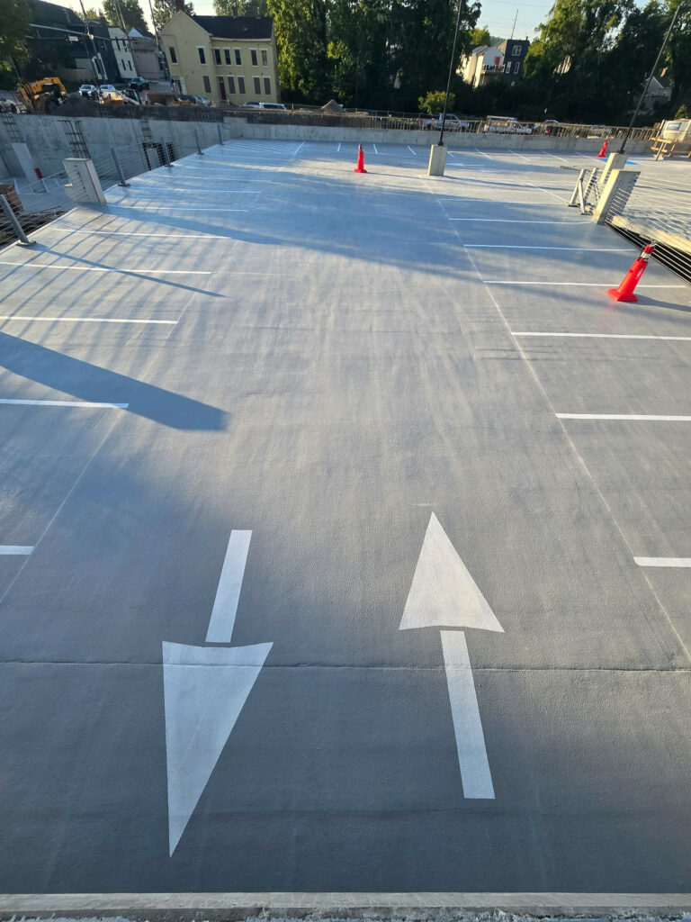 Concrete parking deck with traffic markings and construction barriers"