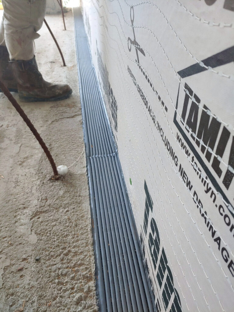 Ribbed floor expansion-joint cover beside a wall under construction"