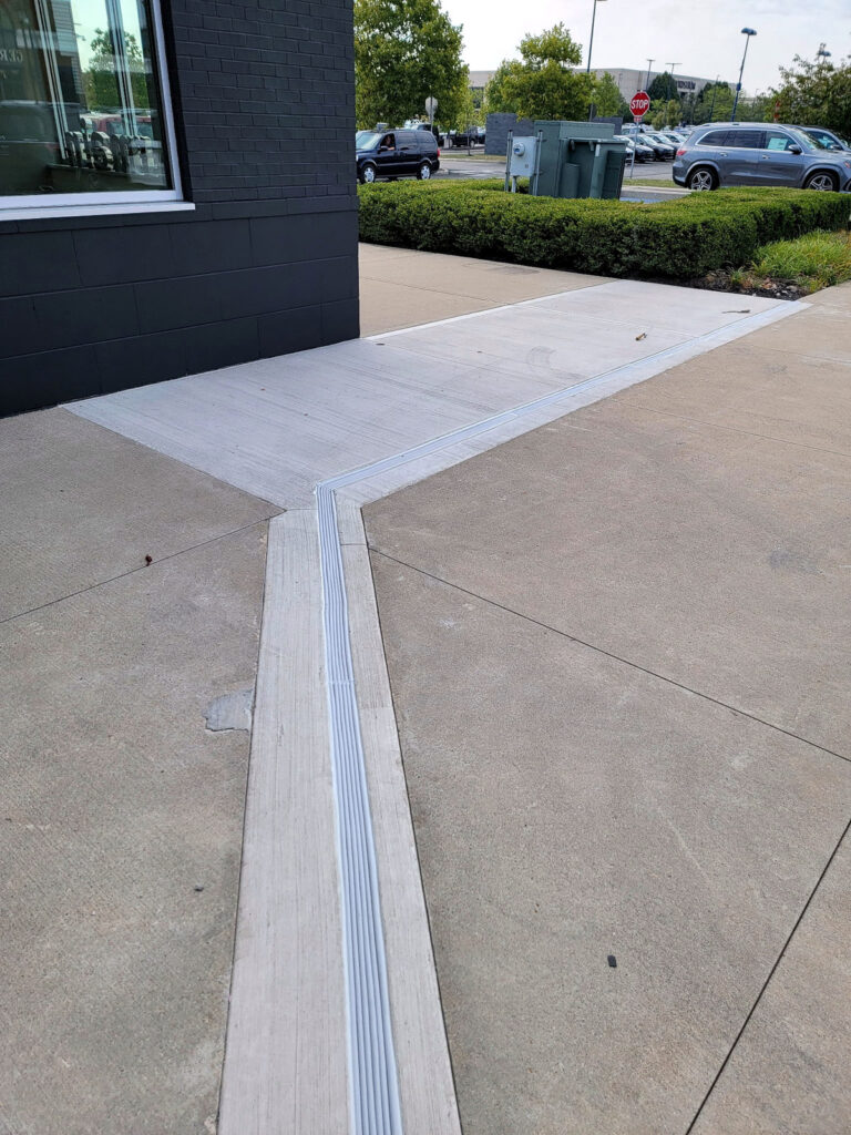 Expansion-joint cover crossing a concrete entrance walkway"