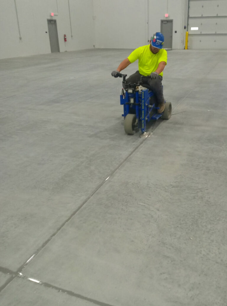 Worker operating equipment along an interior concrete floor"