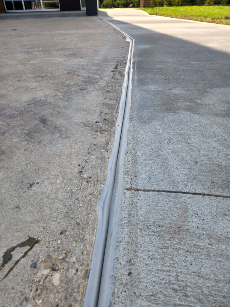 Exterior concrete joint cover approaching a building entrance"