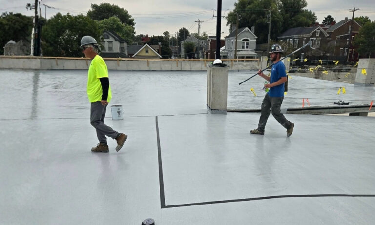 Crew working with long-handled tools on a concrete deck"