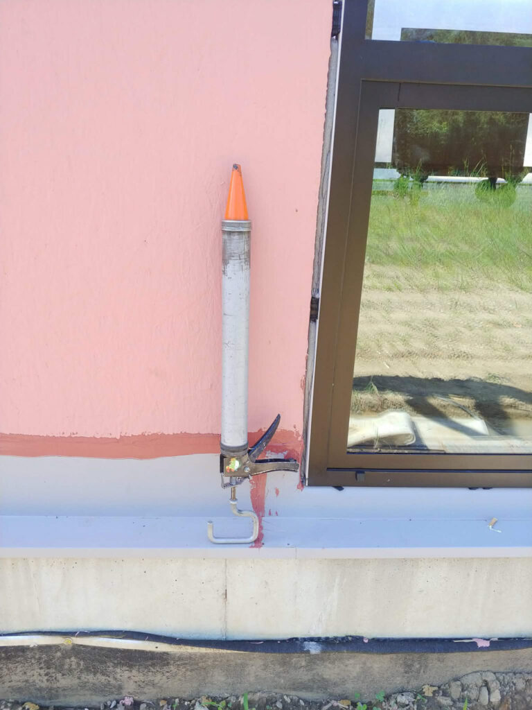 Caulking gun at a window-sill joint"
