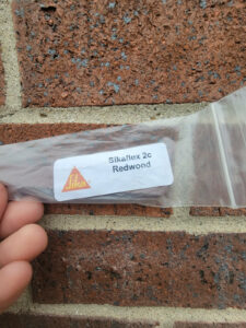Sikaflex-2c-Buff-sealant-sample-held-against-brickwork-and-masonry_NKY