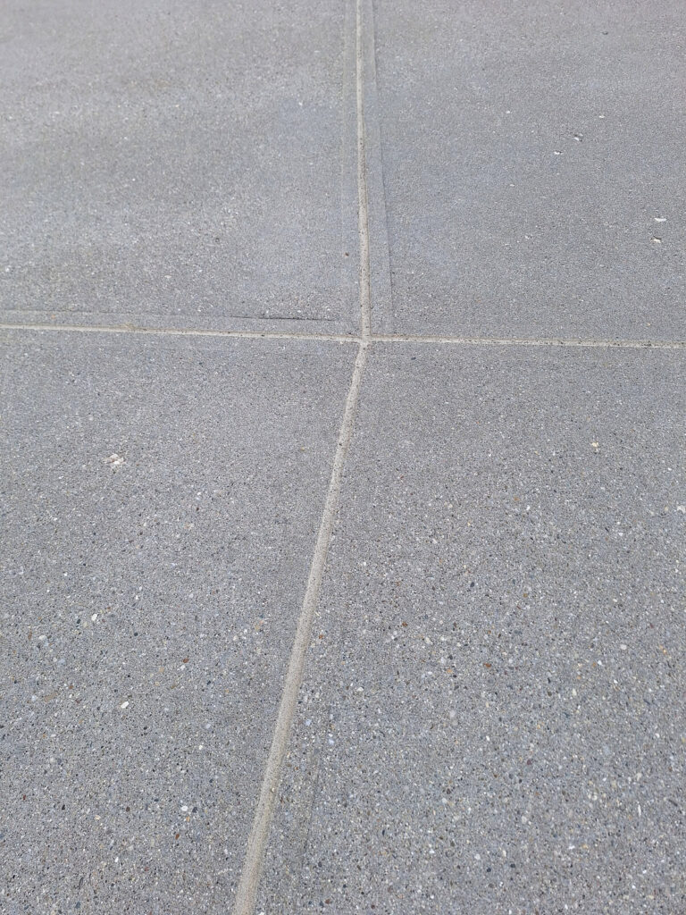 AFTER - Finished concrete joint sealant along a residential garage driveway entrance."