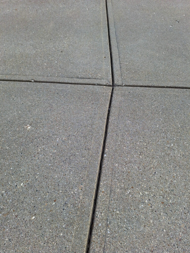 BEFORE Finishing concrete joint sealant & driveway cleaning.  For a residential garage driveway entrance."