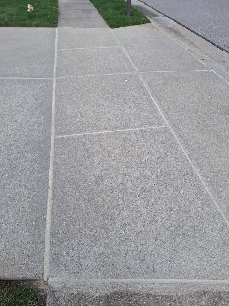 AFTER - Refinishing concrete joint sealant along a residential garage driveway entrance."